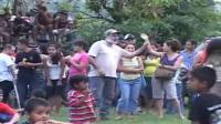 Señor de barba blanca sostiene el brazo de una mujer mientras explica a un grupo de personas