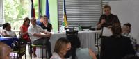 Personas escuchan palabras de la ministra, que está de pie al lado de una pizarr