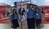 Estudiantes posan al sostener un estandarte