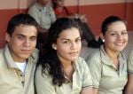 3 estudiantes en uniforme sonríen mientras ven a la cámara.