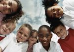 Grupo de niños en círculo ven hacia la cámara. 